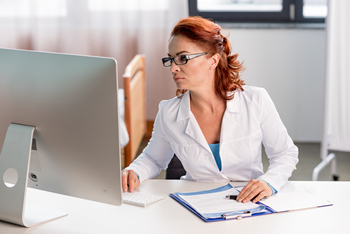 A woman sits at a desk, focused on her computer screen as a USDA loan underwriter.  
